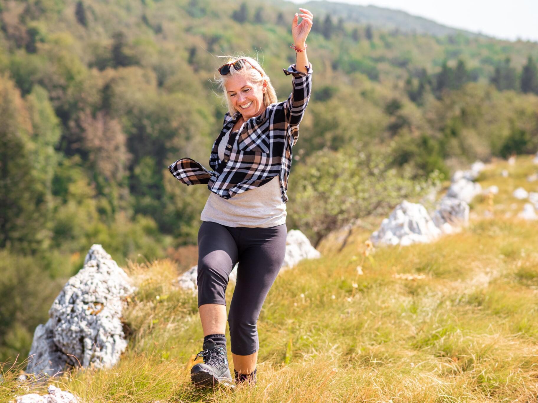 Blonde lachende Frau ist in der Natur und macht Bewegung