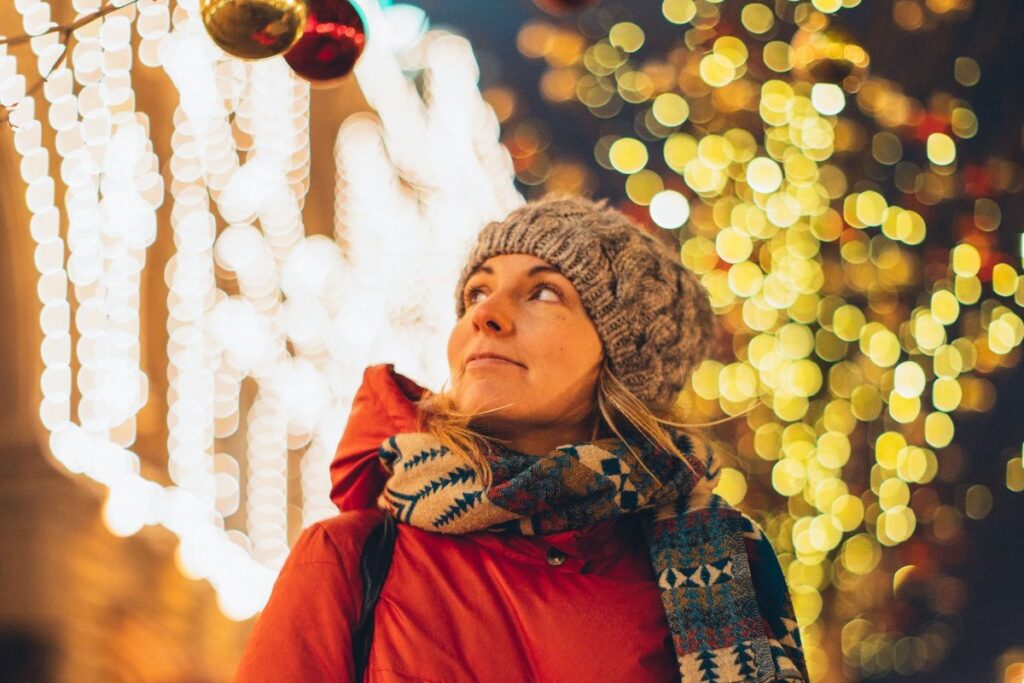 Frau genießt Weihnachtslichter – Weihnachtsstress vermeiden und die Weihnachtszeit entspannt genießen